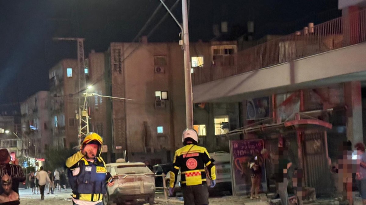 Integrantes de equipos de emergencia, bomberos y policía, trabajan en el área donde un proyectil iraní impactó provocando el derrumbe de un edificio en la madrugada de este domingo.