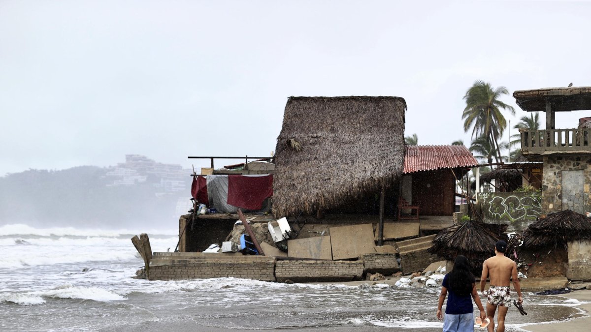 Personas que observan los estragos causados por el fuerte oleaje e intensas lluvias, en Acapulco (México).