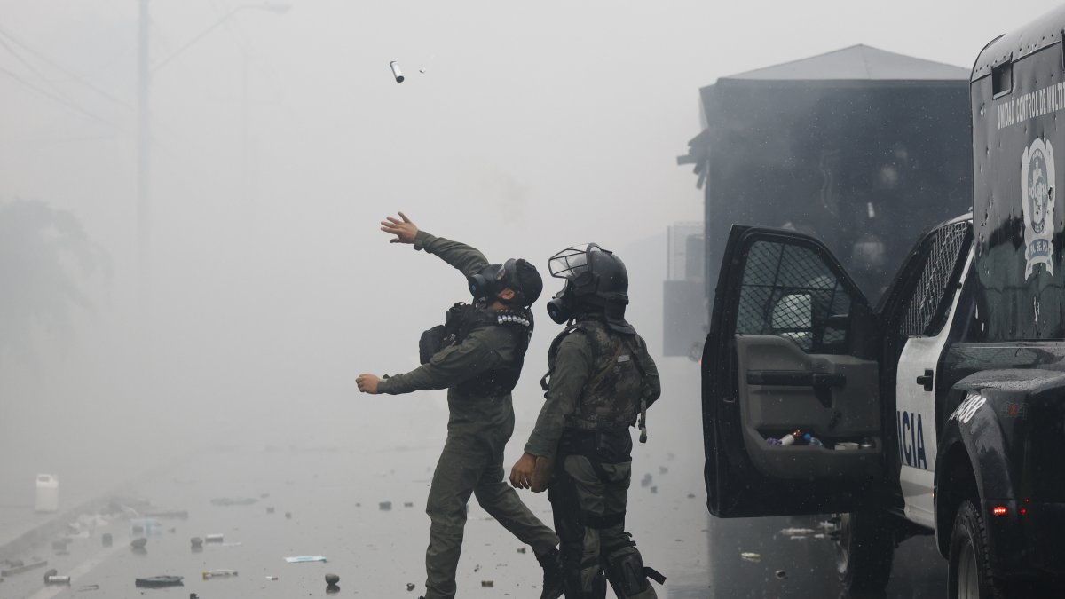 Un integrante de la Unidad de Control de Multitudes (UCM) lanza una granada de gas lacrimógeno durante una manifestación este sábado