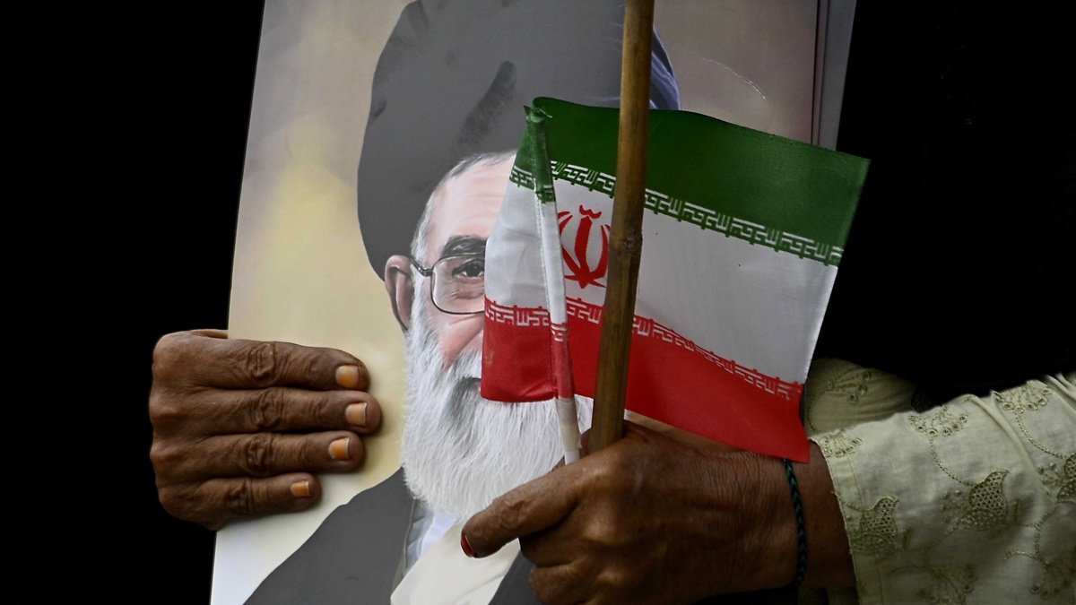Un musulmán chiita pakistaní sostiene un retrato del líder supremo de Irán, Alí Jamenei, y una bandera nacional de Irán durante una manifestación en solidaridad