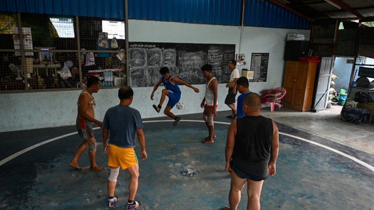 Fotografía de jugadores participando en un partido del tradicional deporte birmano de chinlone en una cancha de Yangon.