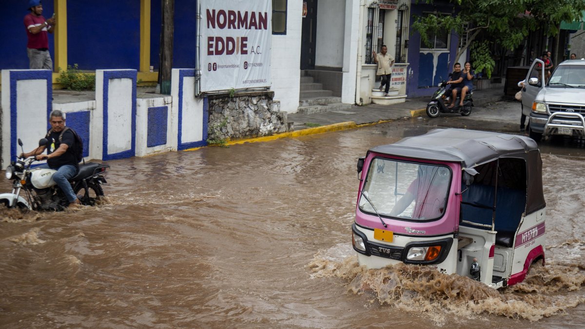 Conductor de moto taxi que circula por una calle inundada, tras el paso del huracán 'Erick', en Oaxaca (México).