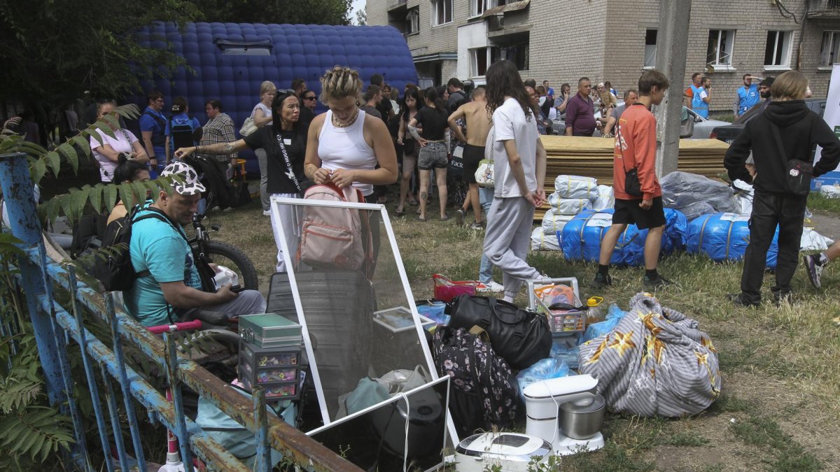 Residentes sentados con sus pertenencias cerca de un edificio residencial dañado tras un bombardeo masivo ruso en la ciudad de Dnipropetrovsk, Ucrania