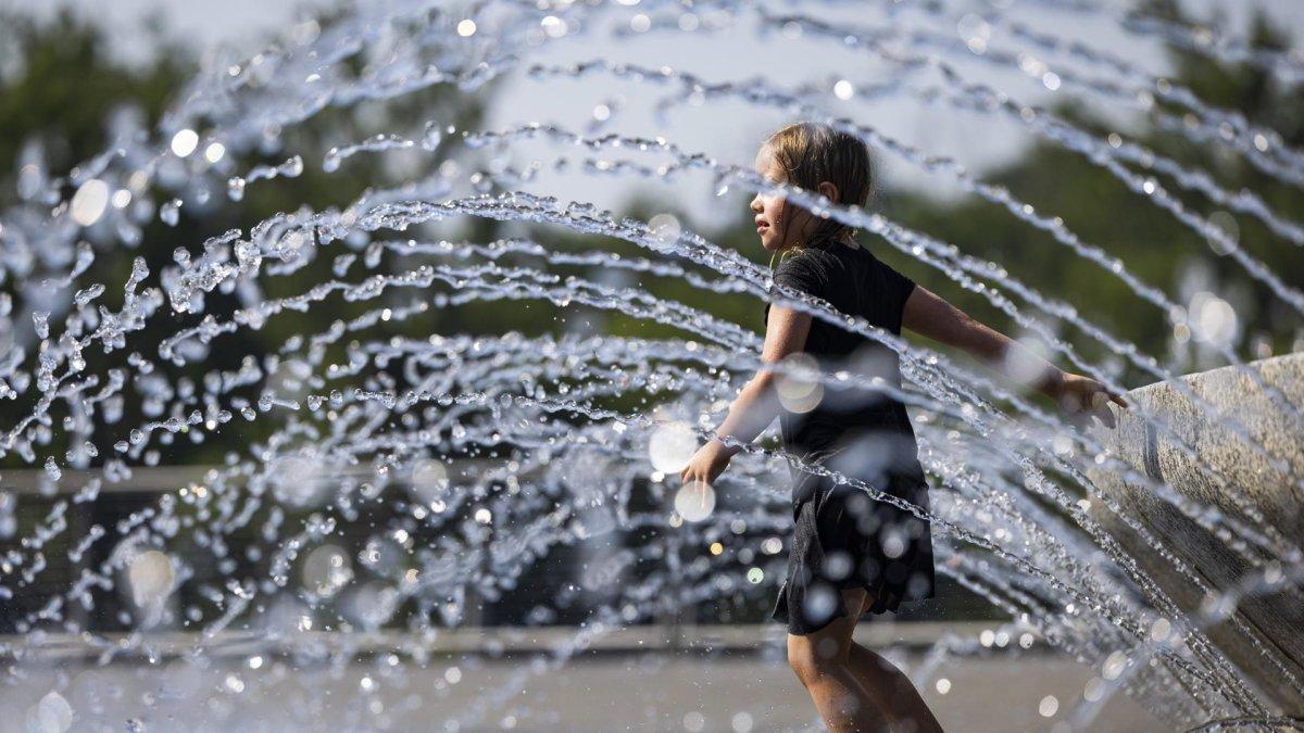 Una niña se refresca en una fuente de agua en Georgetown Waterfront Park en Washington (Estados Unidos).