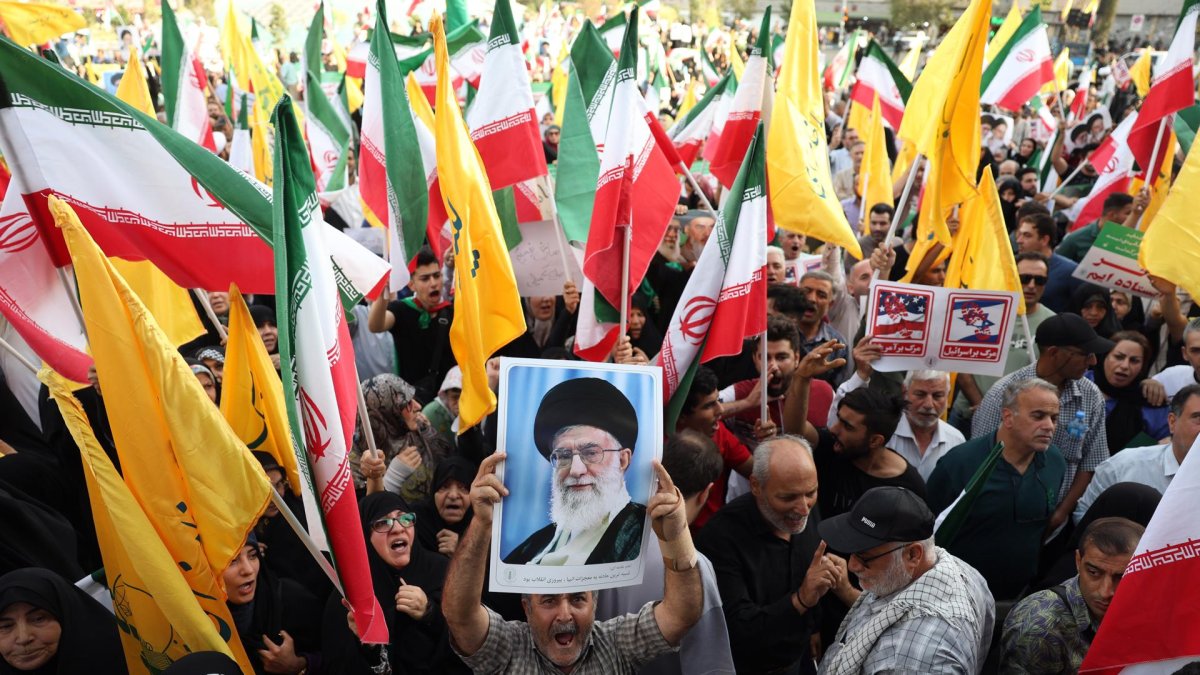 Un iraní sostiene un retrato del líder supremo iraní, el ayatolá Alí Jamenei, entre banderas nacionales de Irán durante una manifestación en Teherán, Irán, el 24 de junio de 2025.