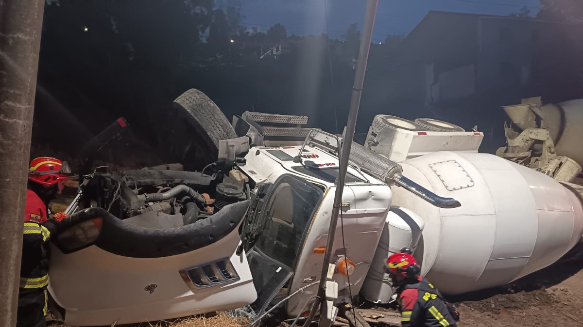 Bomberos Quito verifica volcamiento de vehículo MIXER marca MACK color blanco sobre la vía causando daños en un poste de alumbrado eléctrico.