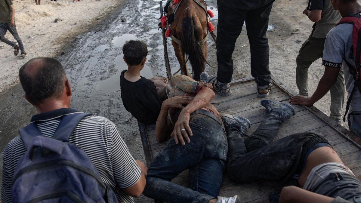 Palestinos ayudan a dos hombres heridos por el ejército israelí, mientras intentaban recoger paquetes de alimentos, en la franja norte de Gaza, el 22 de junio de 2025.