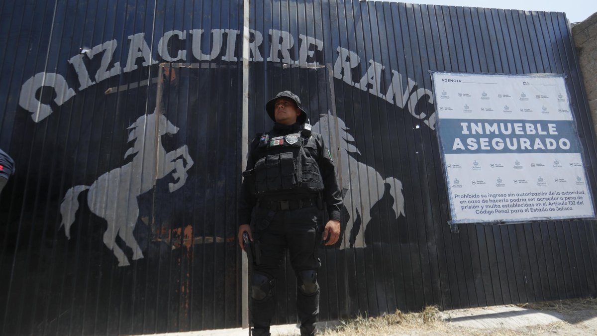 Integrante de la fiscalía estatal resguardando la entrada al Rancho Izaguirre en el municipio de Teuchitlán, Jalisco (México).