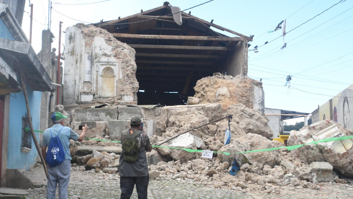 Personas observan este miércoles una edificación destruida por los temblores ocurridos el martes, en Santa María de Jesús (Guatemala).