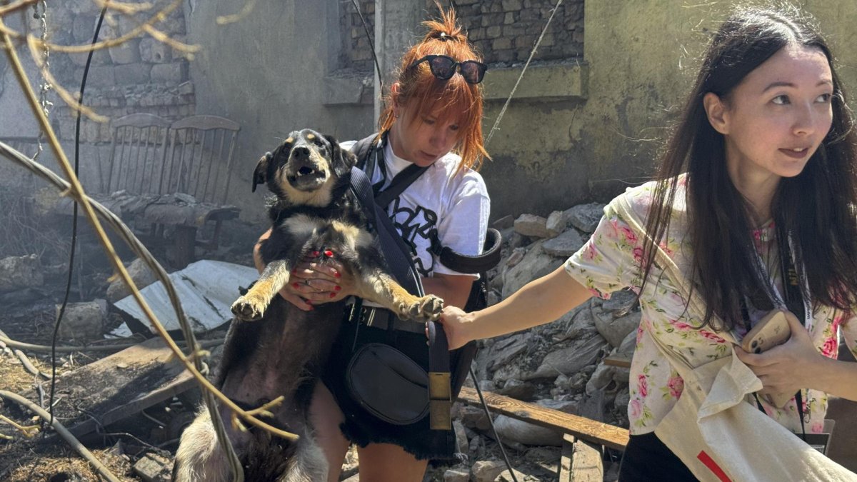 Chicas locales llevan un perro en el lugar de un ataque con drones en Odesa, Ucrania, el 11 de julio de 2025.