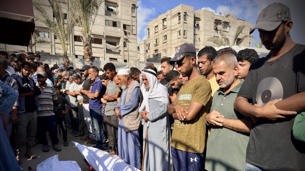 Personas rezan tras la llegada de los muertos bajo fuego israelí durante un bombardeo contra tiendas de campaña, en el sur de Gaza.