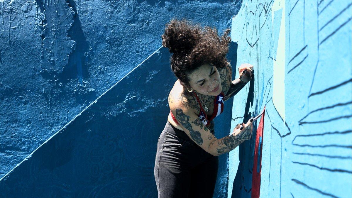 La artista Karina 'Kau' Taveras pinta un mural este miércoles, en la Perla en San Juan (Puerto Rico).