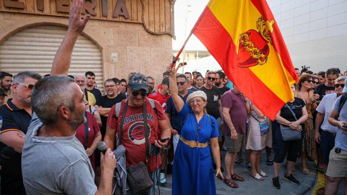 Una mujer con una bandera de España con el sagrado corazón de Jesús en la concentración de este 15 de julio de 2025, en Torre Pacheco (Murcia).