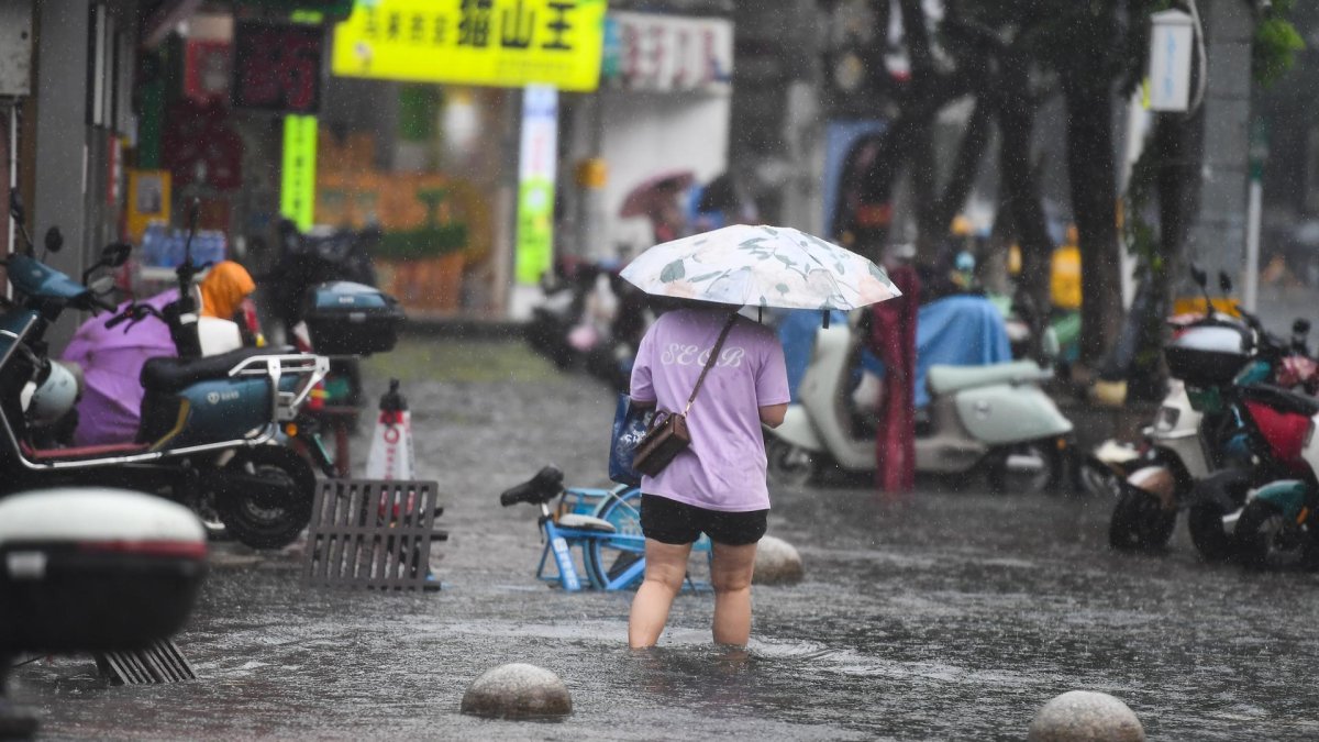 Un peatón camina a través de una zona inundada en Haikou, provincia de Hainan, China, el 20 de julio de 2025.