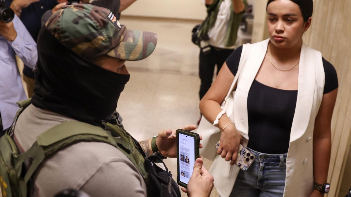 Un agente federal usa información en su teléfono mientras detiene a una mujer fuera de las audiencias del tribunal de inmigración Nueva York, Nueva York, EE. UU..