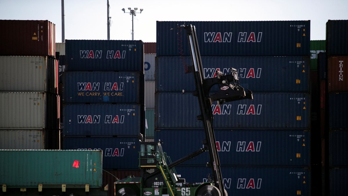Un empleado portuario maniobra junto a pilas de contenedores en el puerto de Los Ángeles.