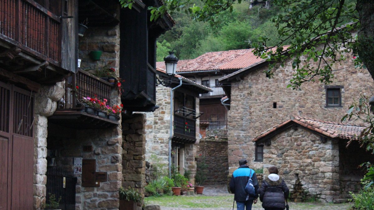 Turismo. Una pareja de visitantes da un paseo por un pintoresco pueblo rural de España para adentrarse en el agroturismo que los atrajo.