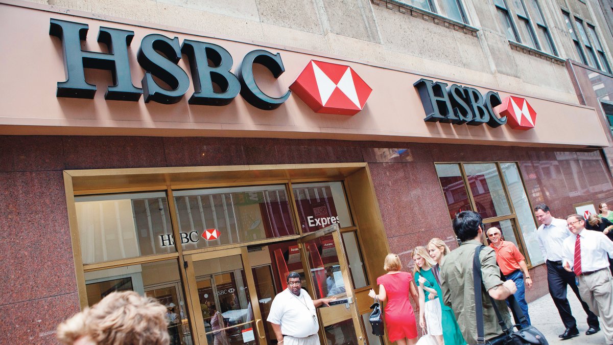 La gente camina por delante de una de las sucursales del Banco HSBC.