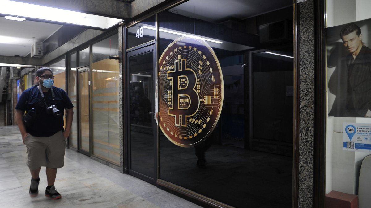 Un hombre caminando frente a una tienda de criptomonedas el 22 de febrero de 2022, en la zona bancaria de Buenos Aires (Argentina).