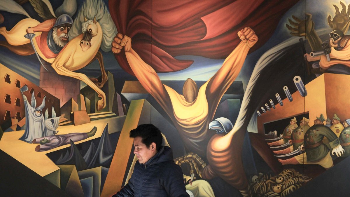 Una persona camina frente a un mural del pintor Miguel Alandia Pantoja en el Museo Nacional de Arte en La Paz (Bolivia).