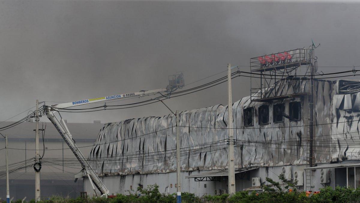 Integrantes del cuerpo de bomberos de Paraguay intentan apagar un incendio este domingo, en el Parque Industrial Logístico Nuestra Señora de la Asunción, en Luque.