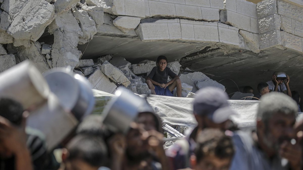Un niño observa un grupo de palestinos agolpados con sus ollas esperando recibir alimentos de un comedor social en la Franja de Gaza.