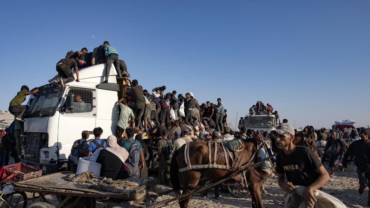 Palestinos desplazados internos suben a camiones de ayuda para conseguir comida en el sur de la Franja de Gaza, el 4 de agosto de 2025.