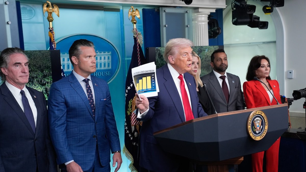 El presidente de Estados Unidos, Donald Trump, sostiene un documento junto al secretario de Defensa, Pete Hegseth (2-i), mientras se dirige a los medios de comunicación en Washington.