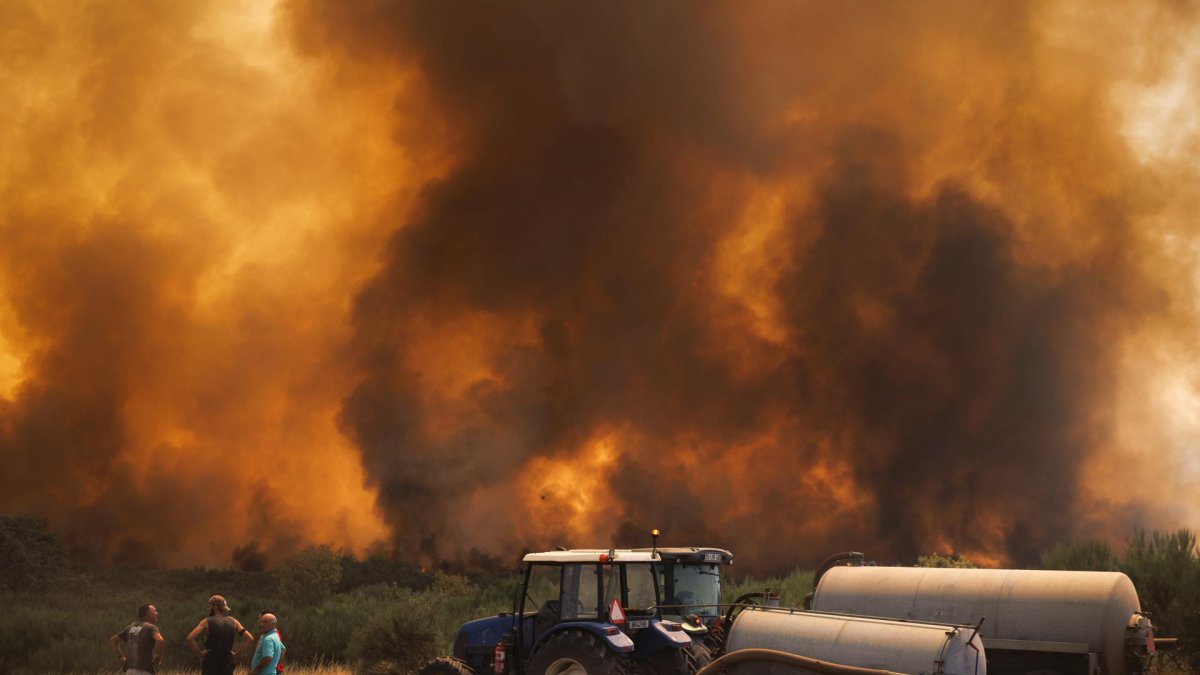 Varios vecinos observan el incendio forestal en Alvite, Moimenta da Beira, Viseu, Portugal.