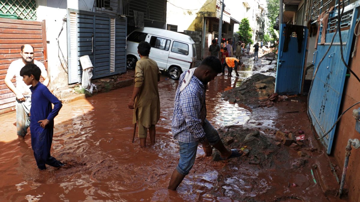 La gente camina entre los escombros de la calle inundada tras varios días de fuertes lluvias en Islamabad, Pakistán, el 6 de agosto de 2025.