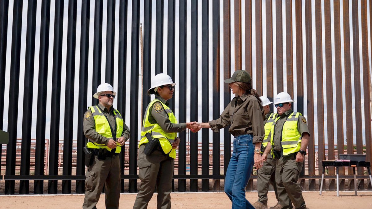 Secretaria de Seguridad Nacional de Estados Unidos, Kristi Noem saludando a un funcionario en frente del muro fronterizo entre Estados Unidos y México.