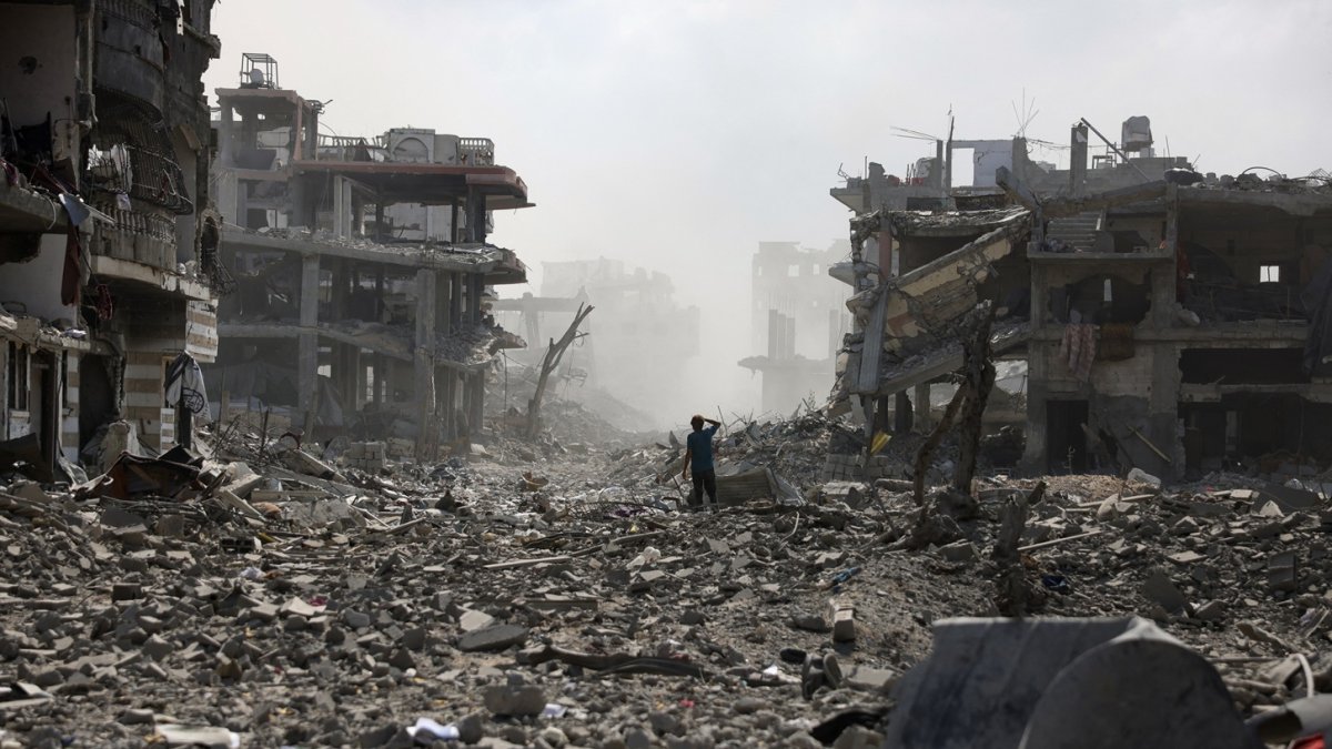 Un joven palestino permanece de pie en una calle sembrada de escombros tras una explosión en el barrio de Saftawi, al oeste de Jabalia, en el norte de la Franja de Gaza, el 25 de agosto de 2025.