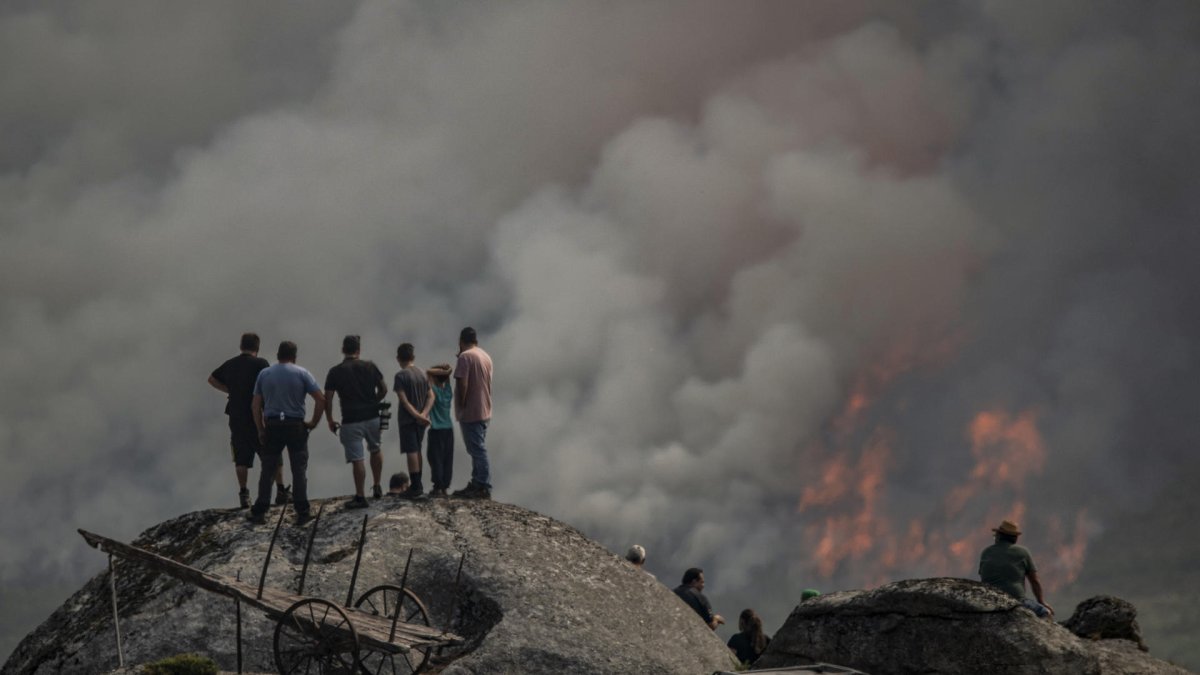 Varias personas observan el incendio forestal declarado ayer en Avión (Ourense), este lunes 25 de agosto de 2025.
