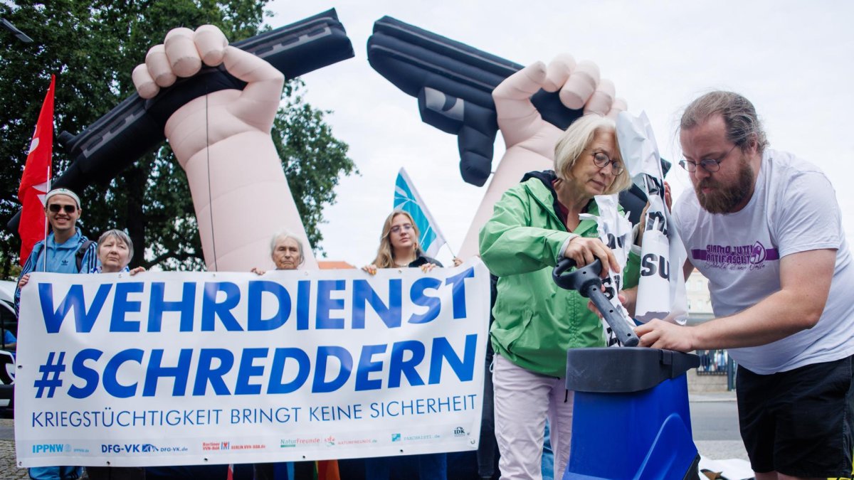 Manifestantes rompen simbólicamente un cartel en relación con la ley del servicio militar, el 27 de agosto de 2025, Alemania.