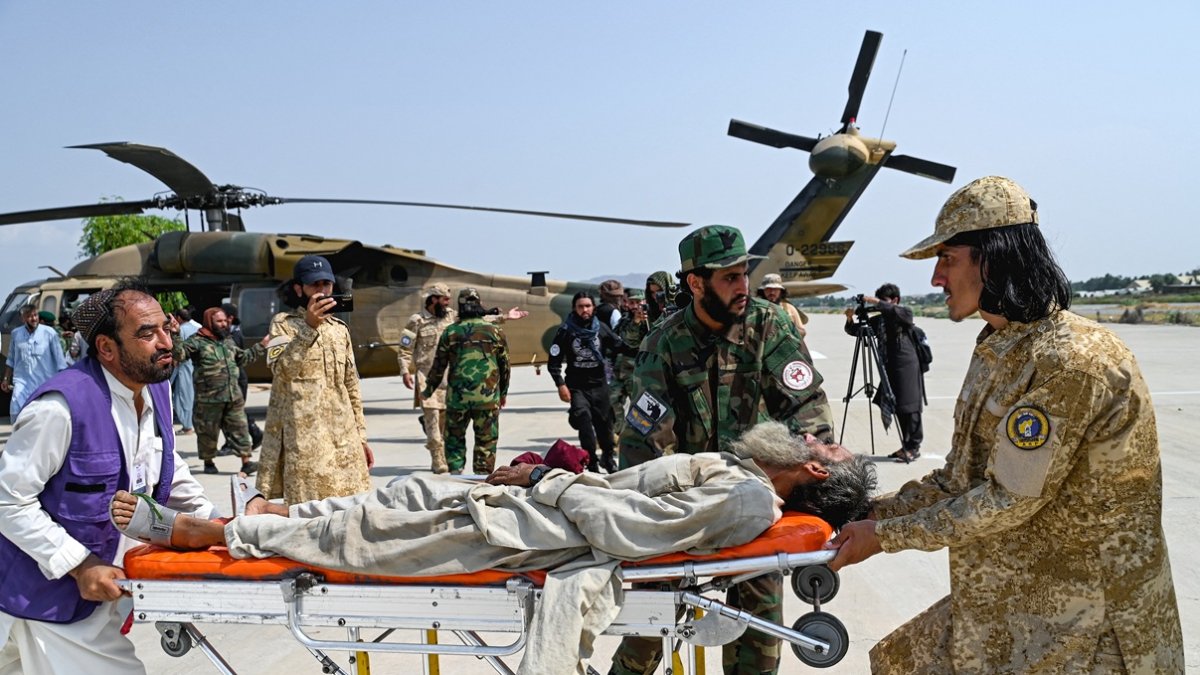 Voluntarios afganos y personal de seguridad talibán transportaron a una víctima del terremoto evacuada en un helicóptero militar desde el distrito de Nurgal de la provincia de Kunar.