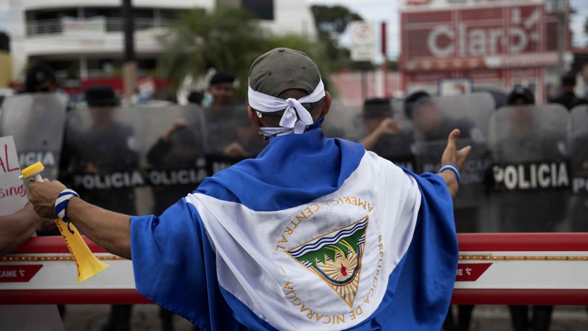 Joven con una bandera de Nicaragua frente a Policías, en Managua (Nicaragua).