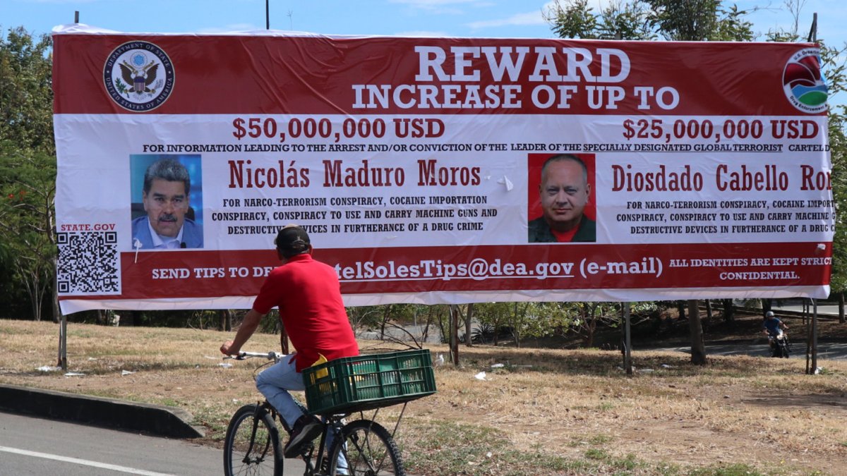 Recompensa. Un hombre observa una valla con el anuncio de recompensa y la imagen del presidente de Venezuela, Nicolás Maduro, y de su ministro de Relaciones Interiores.