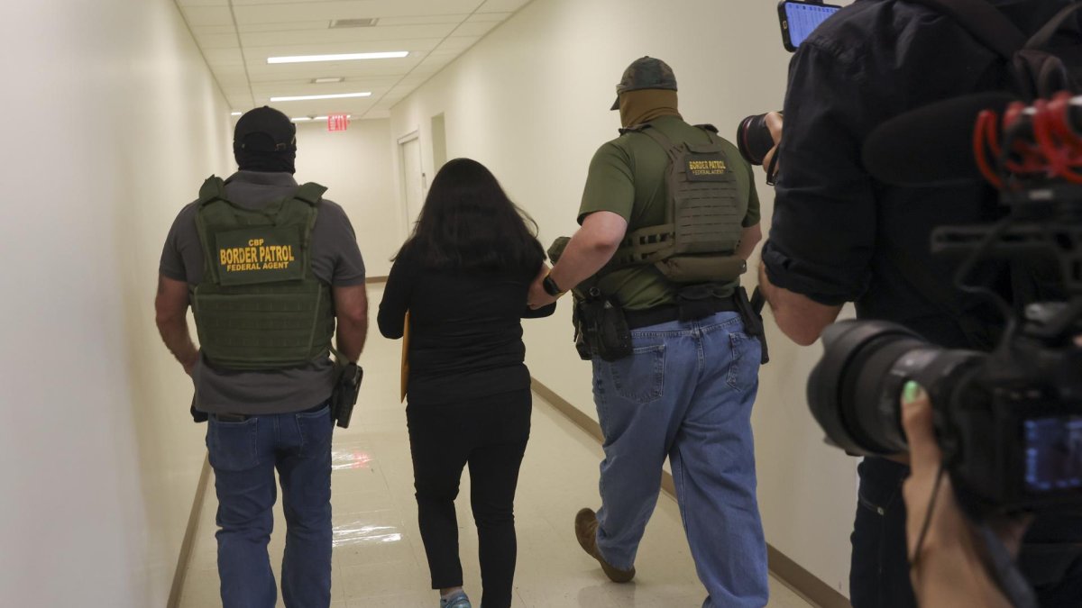 Agentes federales deteniendo a una persona dentro de un edificio federal donde se celebran audiencias de inmigración, en Estados Unidos.