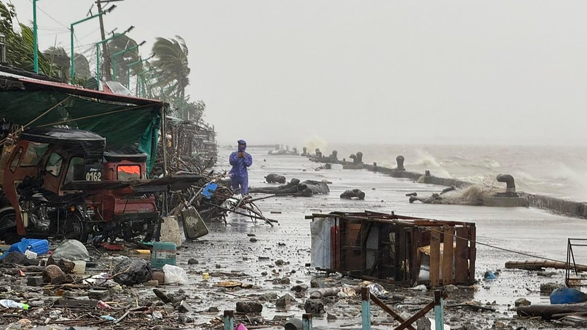 Un hombre se encuentra cerca de escombros en una carretera costera en medio de fuertes lluvias debido a los patrones climáticos del súper tifón Ragasa en la ciudad de Aparri, Filipinas.
