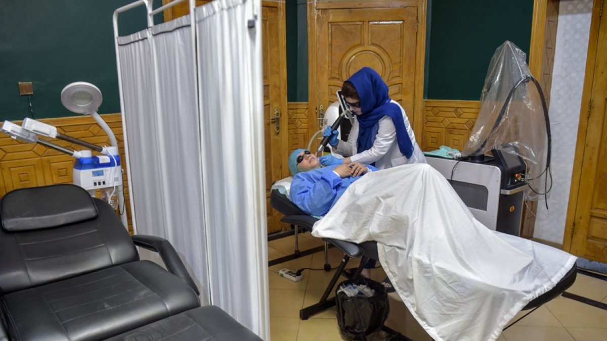 Un miembro del personal médico realiza un tratamiento con láser en el rostro de una mujer afgana en una clínica de belleza en Kabul.