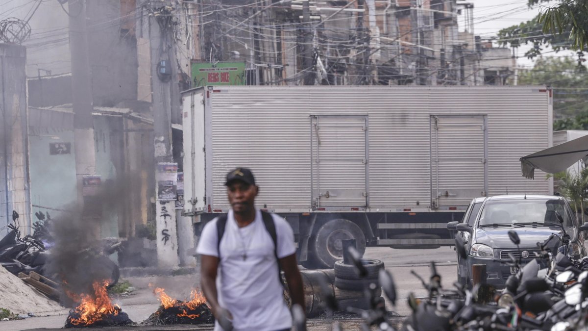 Una persona camina frente a barricadas en llamas durante un operativo policial este viernes, en Río de Janeiro (Brasil)