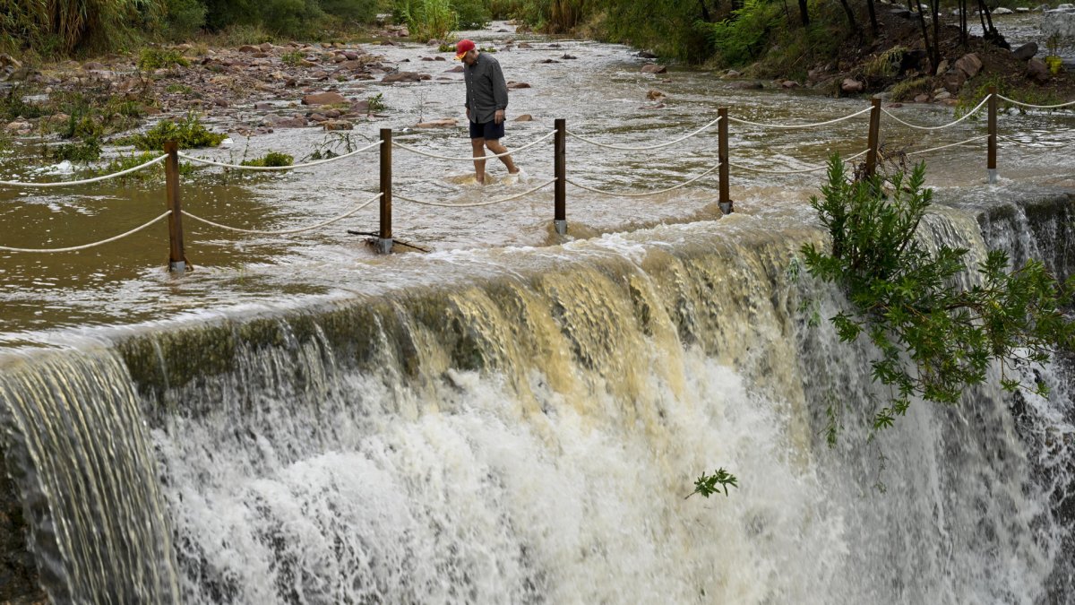 Un hombre cruza un badén inundable durante este lunes 29 de septiembre de 2025, bajo aviso rojo (riesgo extremo) en España.