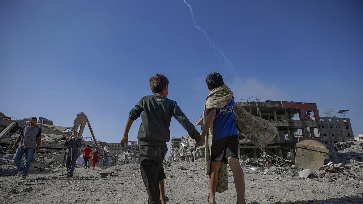 Palestinos caminan por una calle entre los escombros de edificios destruidos durante un alto el fuego entre Israel y Hamás en virtud de la primera fase del plan de paz de Gaza.