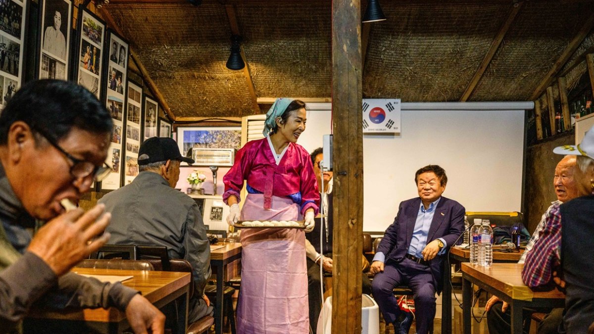 Son Yun-kyung (de pie) sirve dumplings mandu al estilo norcoreano a personas mayores y refugiados norcoreanos en la isla Gyodong, el 7 de octubre de 2025.