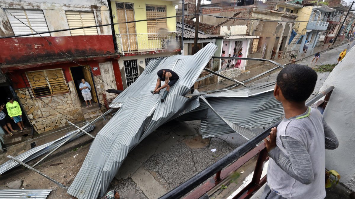 Personas recogen escombros en una calle afectada por el paso del huracán Melissa este miércoles, en Santiago de Cuba (Cuba).