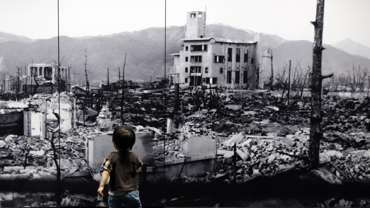 Un niño camina hacia una gran foto de la ciudad de Hiroshima devastada tras la explosión nuclear. (Japón, Estados Unidos).