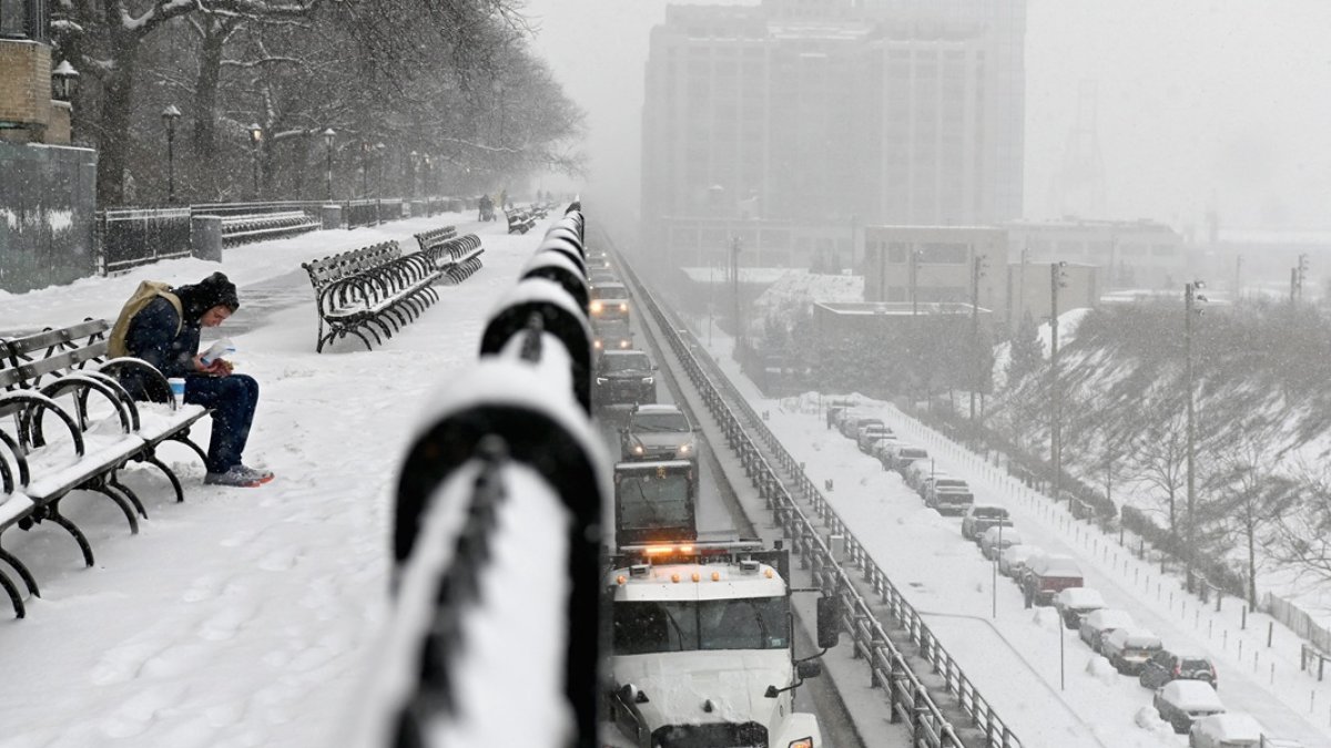 Un hombre se sienta en un banco durante una nevada en Nueva York, en febrero.