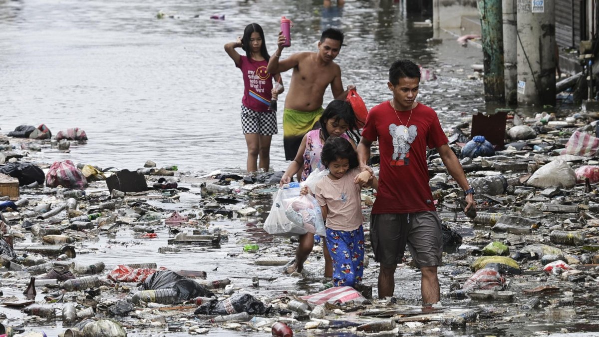 Un grupo de niños camina por las calles inundadas de Manila, Filipinas este lunes tras el paso del tifón Fung-Wong.