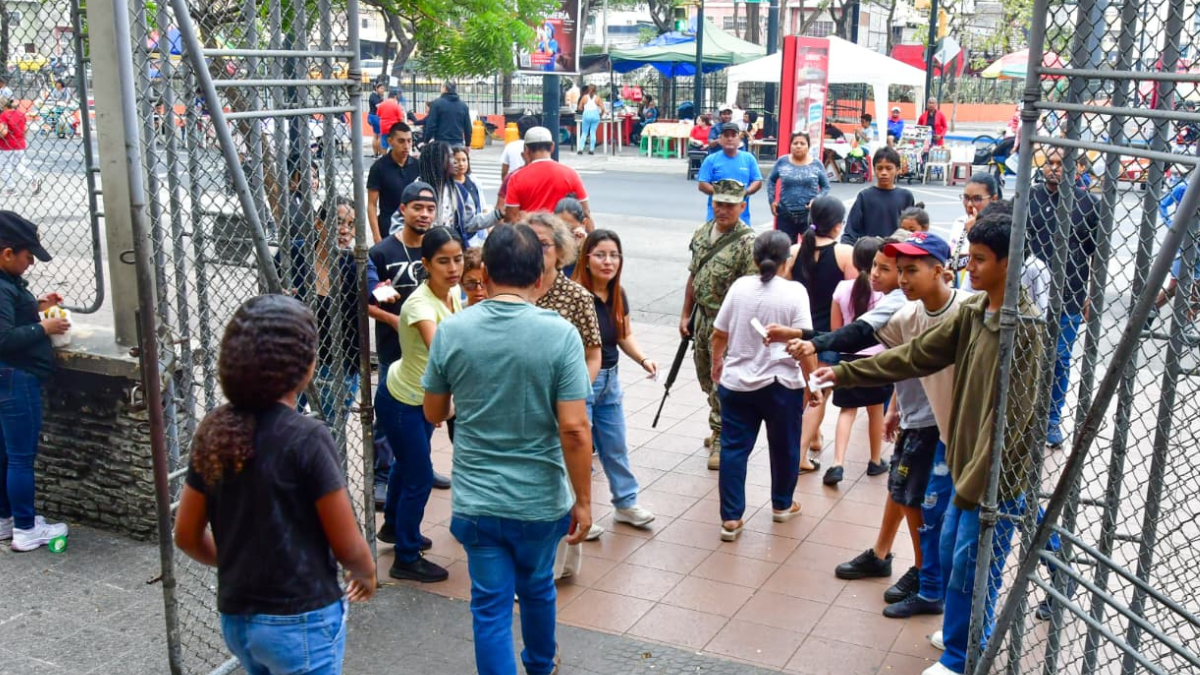 Varias personas, entre niños, tratan de convencer a los electores a que plastiquen con ellos el certificado de votación.