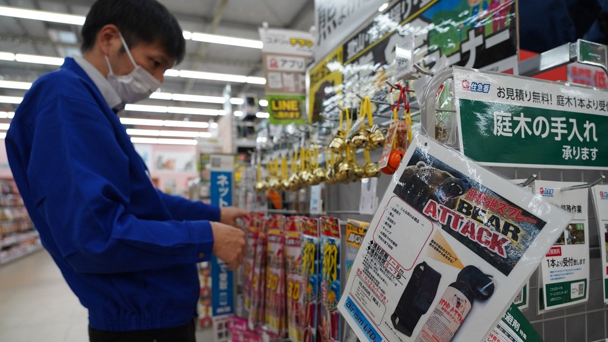Un empleado clasifica campanillas junto a un anuncio de spray para osos en una tienda de Hanamaki, prefectura de Iwate, el 24 de octubre de 2025.